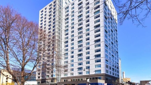 Un edificio a più piani con un design architettonico moderno, caratterizzato da numerose finestre e una struttura ad angolo di rilievo.