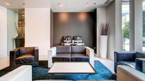 Un'accogliente hall moderna con divano, poltrone, tavolino e schermo televisivo.
