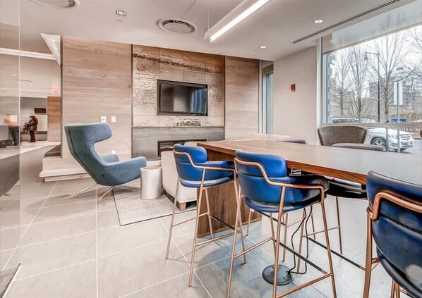 A modern bar area with a long wooden table and blue bar stools.