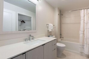 Ein modernes Badezimmer mit großem Spiegel, Waschbecken, Toilette und Duschbereich.