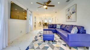 A modern living room with a blue sectional sofa, a ceiling fan, and a geometric patterned rug. - Pet-Friendly St Augustine Home: 2 Mi to Downtown! (St. Augustine)