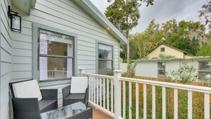 A covered porch with wicker furniture and a glass table, white railings, and a view of neighboring houses. - Pet-Friendly St Augustine Home: 2 Mi to Downtown! (St. Augustine)