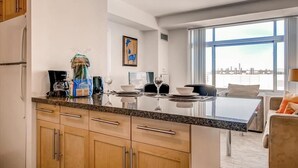 A modern kitchen with granite countertops, wooden cabinets, and a dining area with a glass table and chairs. - Stylish Cambridge Stay Near MIT& Kendall Square (Cambridge)