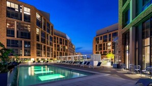 Ein Poolbereich mit Liegestühlen und einem Pool, umgeben von modernen Gebäuden mit großen Fenstern.