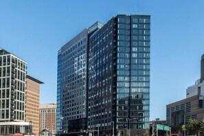 A modern high-rise building with a glass facade and multiple floors. - Modern One Bedroom Apartment in Boston Seaport (Boston)