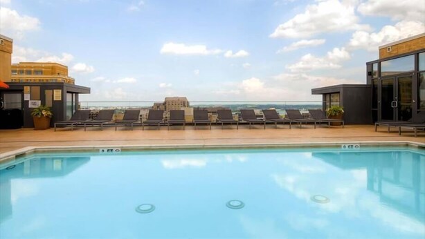 A rooftop pool with lounge chairs and a view of the city skyline. - Spacious 2BR Apt | Work Desk + Internet | Pentagon City (Arlington)