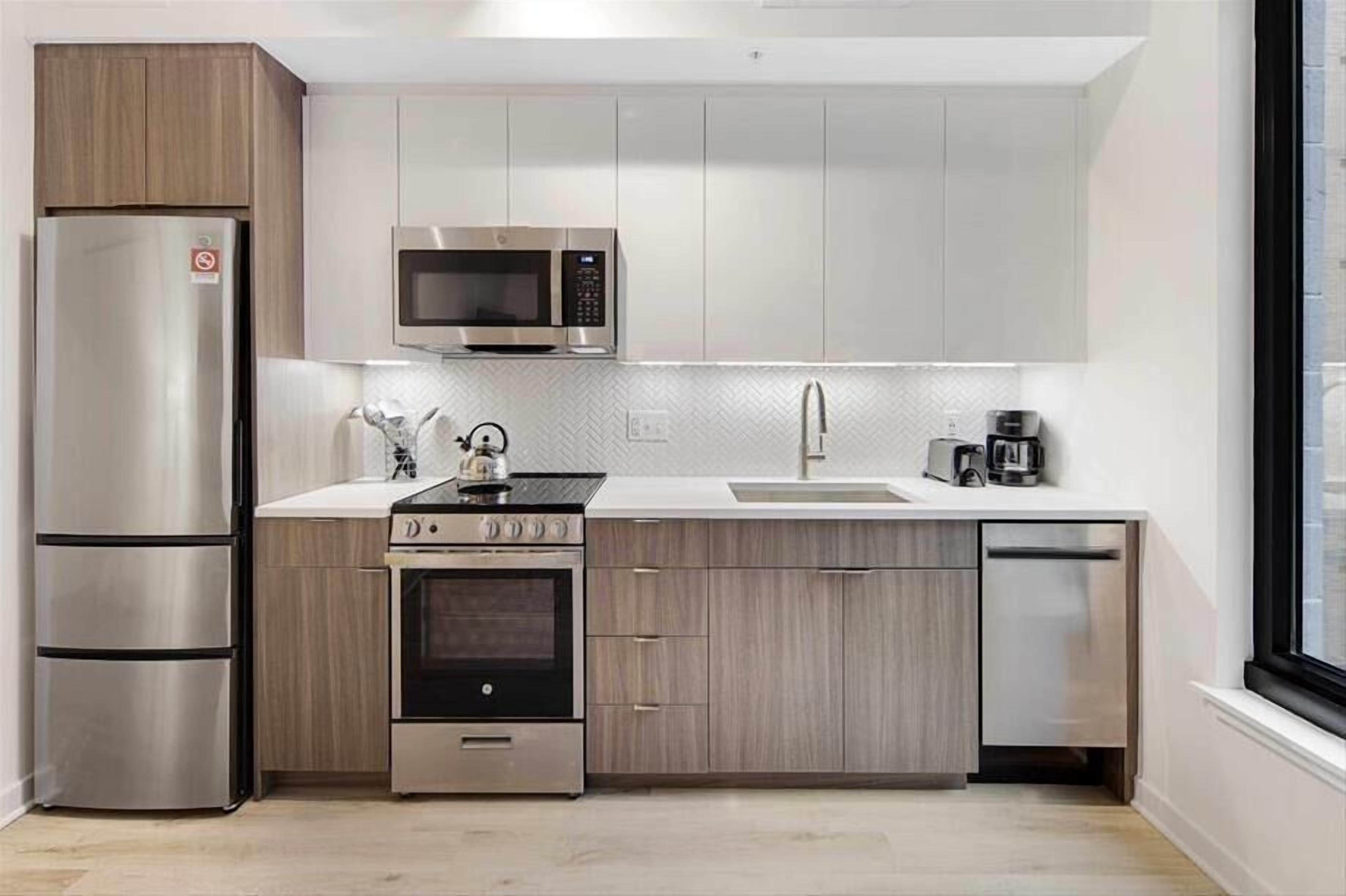 Una cucina moderna con elettrodomestici in acciaio inox, mobili in legno e una finestra che fa entrare luce naturale.