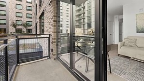 Eine moderne Wohnung mit Balkon, einer Glast ür zum Küchenbereich und einem Wohnzimmer mit Sofa und Teppich.