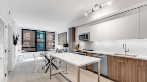 Una cocina moderna con encimera blanca, armarios de madera y un ventanal grande.