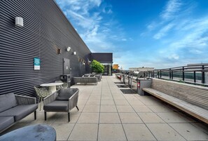 Un espace extérieur aménagé avec un coin salon, un barbecue et une vue sur les bâtiments de la ville.