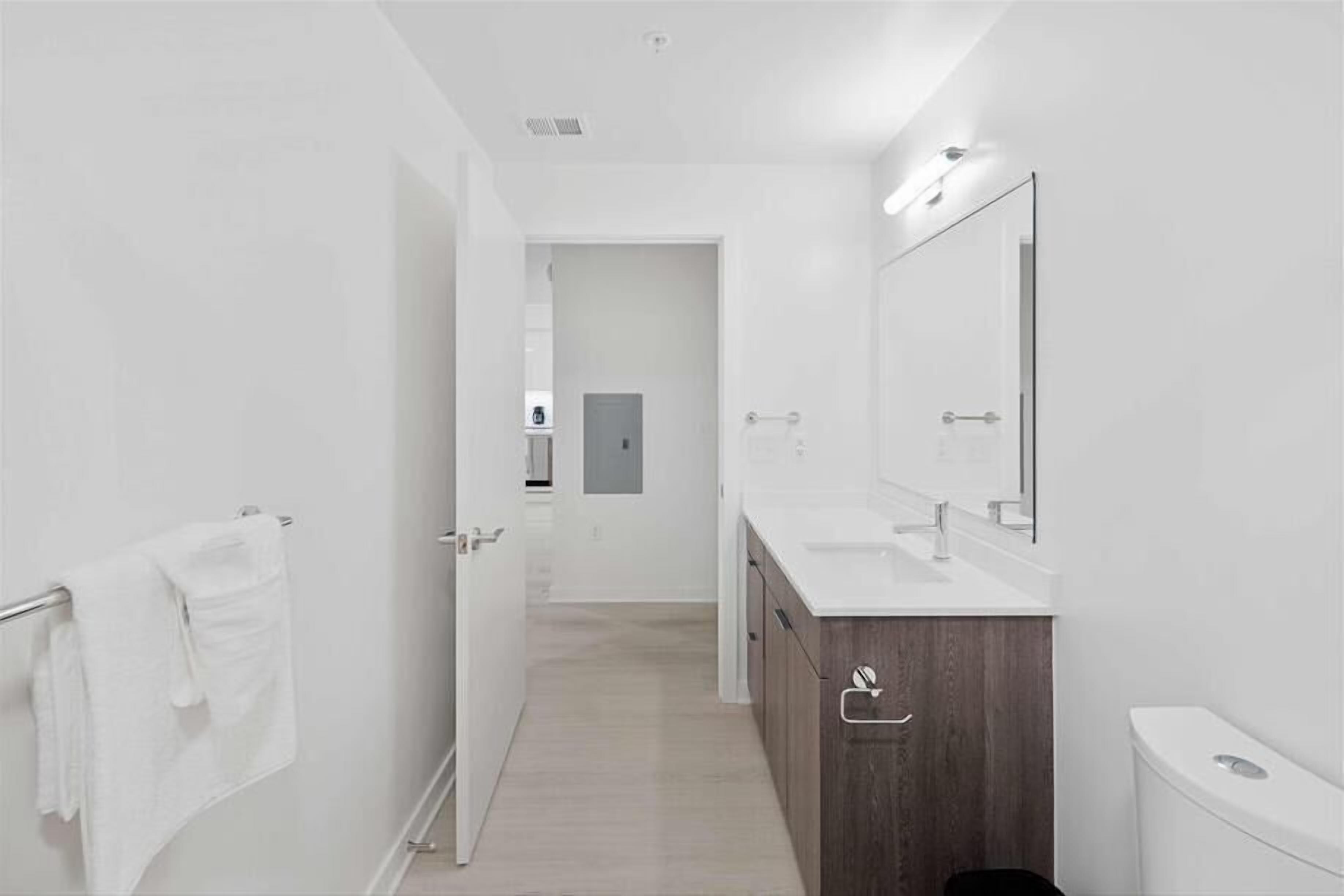 Uma casa de banho moderna com uma sanita, espelho e lavatório brancos.