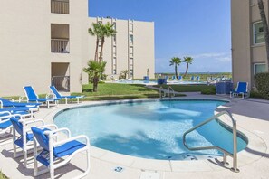 A swimming pool with blue lounge chairs and a palm tree. - Beach House II #303​​​​​​​ | Beachfront Condo • Two Pools • Direct Beach Access (South Padre Island)