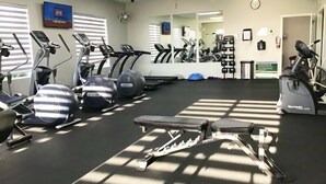 Een fitnessruimte met loopbanden, elliptische trainers en losse gewichten.