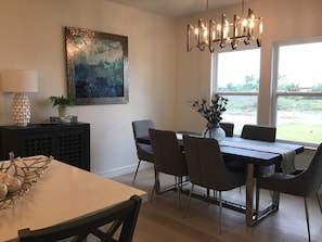 Ein Essbereich mit Tisch, Stühlen, einer Chandelierleuchtre, einem Gemälde und einem Fenster mit Blick.