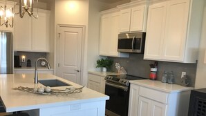 Een moderne keuken met witte kasten, een roestvrijstalen koelkast, een oven en een spoelbak met decoratief middelpunt.