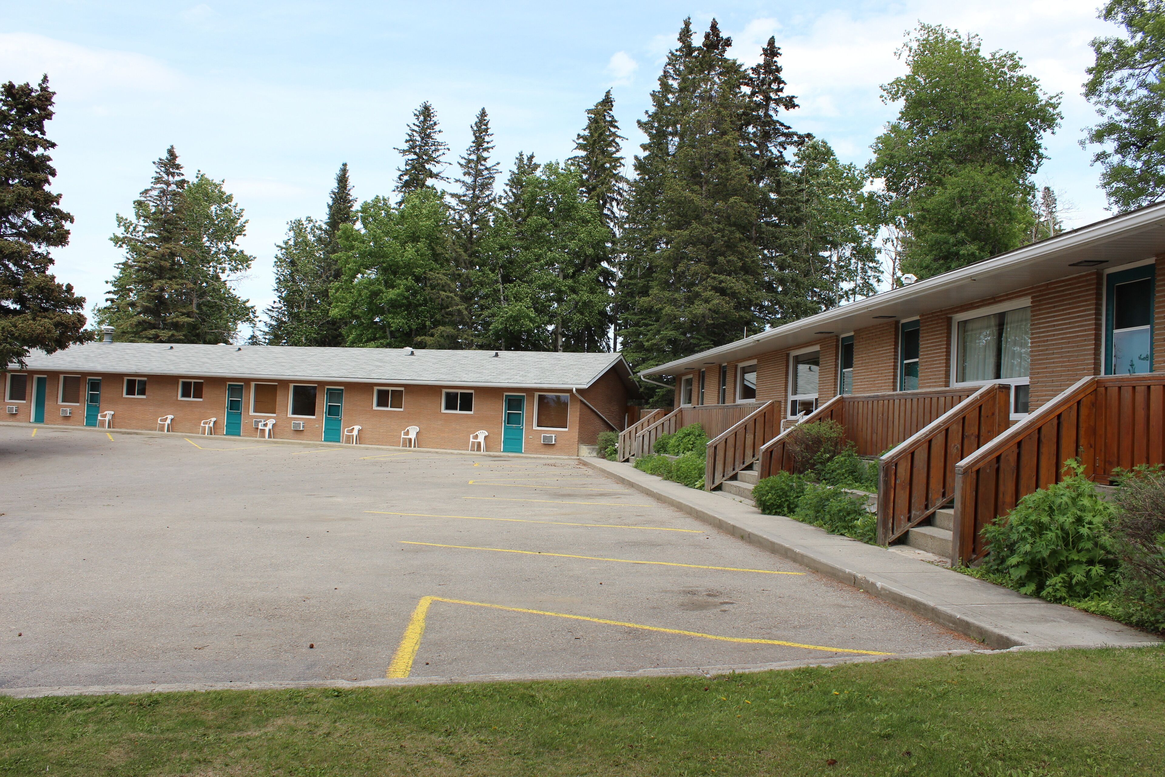 A motel with a parking lot, a building with multiple rooms, and a staircase leading to the entrance.