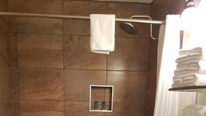A bathroom with a shower, a toilet, and a towel rack. - Pines Motel (Hinton)