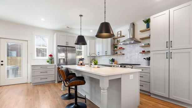 A modern kitchen with white cabinetry, a central island with bar stools, pendant lighting, and a stainless steel refrigerator. - Hot Tub • Fire Pit • Chef’s Kitchen • Near Uptown (Charlotte)