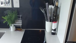 Een keuken met een ingebouwde kookplaat, een lade met keukengerei en een wijnfles op het aanrecht.