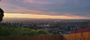 Ein weiter Blick auf eine Stadtlandschaft bei Sonnenuntergang, im Vordergrund ein Holzzaun.