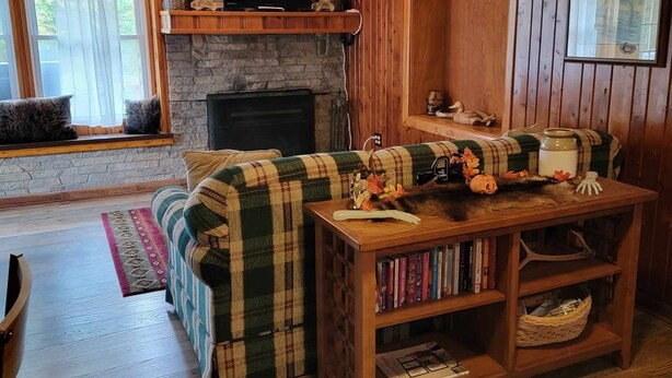 Ein gemütliches Wohnzimmer mit Kamin, Fernseher und Bücherregal.