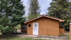 Eine kleine Holzhütte mit einer weißen Tür, einer Satellitenschüssel und einer Terrasse.
