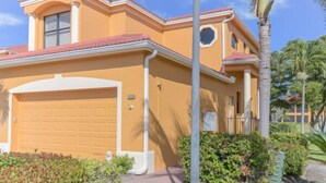 A two-story house with a garage, a small balcony, and a well-maintained garden with palm trees. - Prentiss Pointe Condo - 3 bedroom, 2 bath, 2-Floor Condo in Ft Myers (Fort Myers)