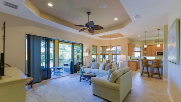 A spacious living room with a sofa, coffee table, and a ceiling fan. There is a sliding glass door leading to a balcony. - Prentiss Pointe Condo - 3 bedroom, 2 bath, 2-Floor Condo in Ft Myers (Fort Myers)