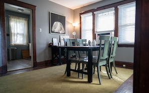 A dining area with a table and chairs, a lamp, and a painting on the wall.