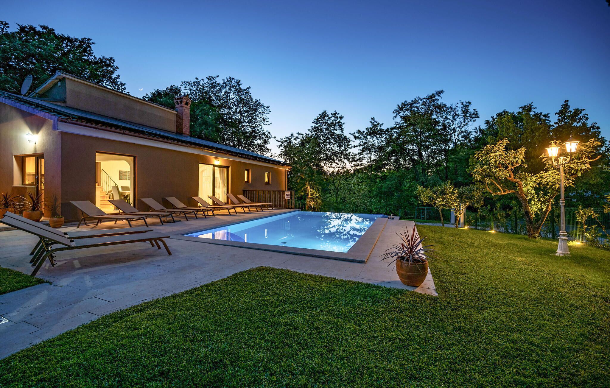A modern house with a swimming pool, lounge chairs, and a well-maintained lawn.