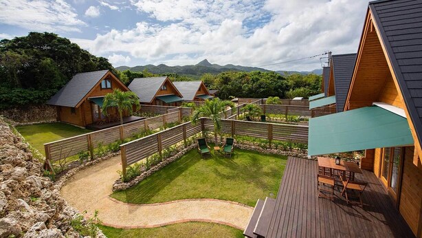 A row of wooden cabins with a grassy yard and a wooden deck. - Logasis Ishigaki Nosoko Villa (Ishigaki)