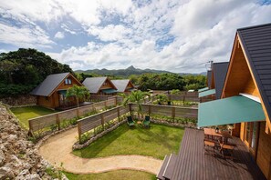Une rangée de cabanes en bois, avec une cour verdoyante et une terrasse en bois.