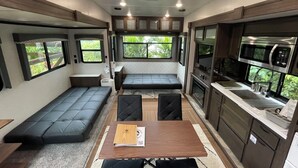 A compact RV interior with a kitchenette, seating area, and large windows. - Logasis Ishigaki Nosoko Villa (Ishigaki)