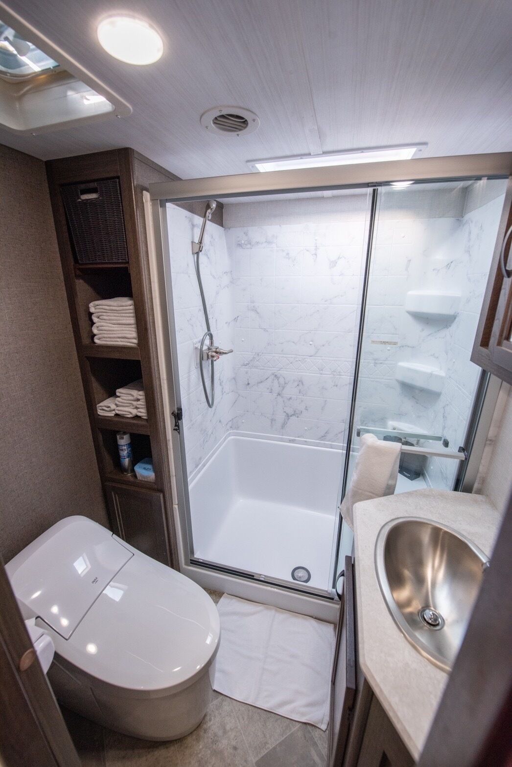 A compact bathroom with a glass-enclosed shower, a toilet, and a sink.