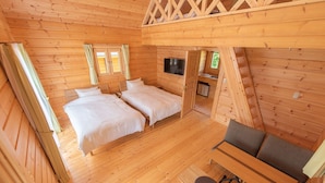 A wooden cabin with two beds, a TV, and a small table with chairs. - Logasis Ishigaki Nosoko Villa (Ishigaki)