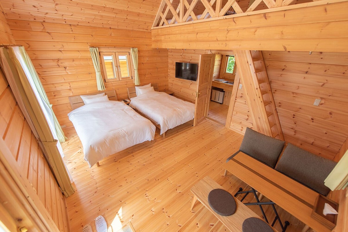 Een houten blokhut met twee bedden, een televisie en een kleine tafel met stoelen.