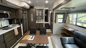A compact RV interior with a kitchenette, dining area, and seating. - Logasis Ishigaki Nosoko Villa (Ishigaki)
