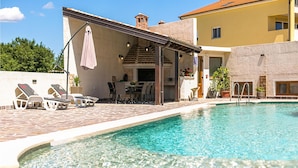 A swimming pool with lounge chairs and a covered patio area.