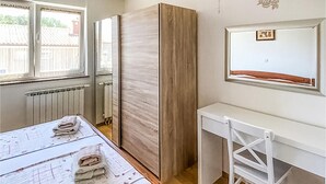 A bedroom with a bed, a desk, and a wardrobe.