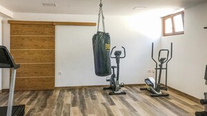 A home gym with a stationary bike, elliptical, and a punching bag.