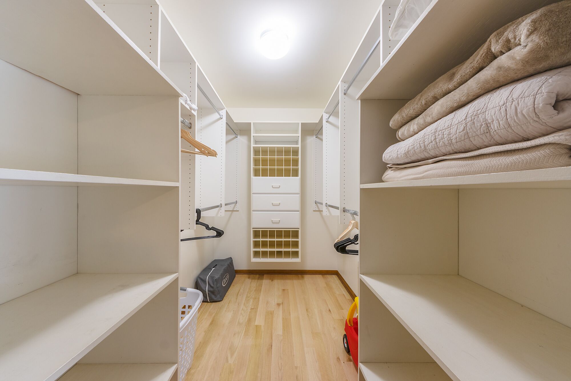 A walk-in closet with open shelves, hanging space, and a central storage unit.