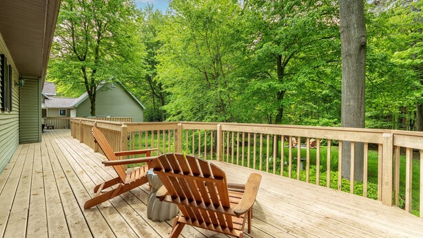 Una terraza de madera con dos sillas Adirondack y una jardinera de piedra.