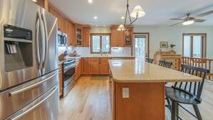 Una cocina moderna con electrodomésticos de acero inoxidable, armarios de madera y una isla central con asientos.
