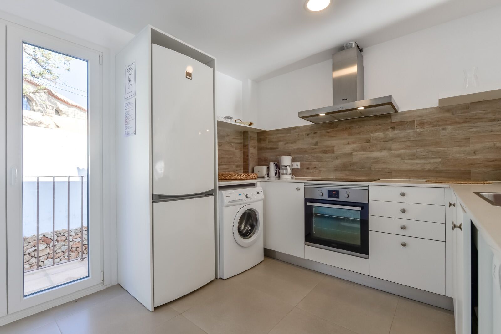 A compact kitchen with a washing machine, oven, and a built-in microwave.