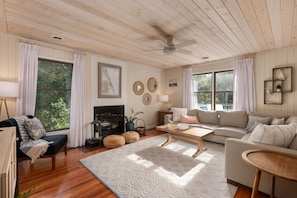 A cozy living room with a fireplace, comfortable seating, and large windows.