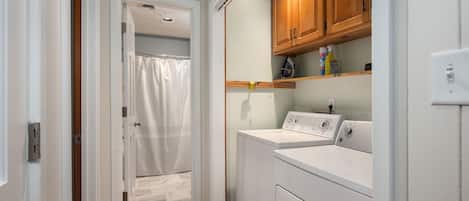 A laundry room with a washing machine, dryer, and wooden cabinets.
