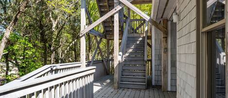 A wooden deck with a railing, leading to a covered area with a sloped roof.