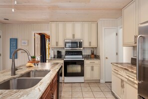A kitchen with a sink, stove, microwave, and cabinets.
