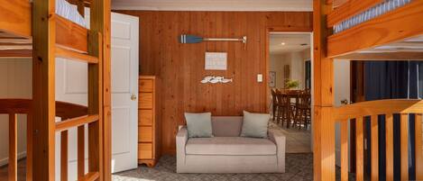 A cozy room with bunk beds, a sofa, and a dining area.