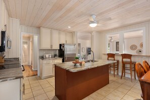 A kitchen with white cabinetry, a central island, and a ceiling fan.